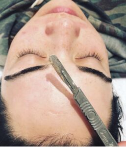 IMG_1122 - Elmira Studio A woman getting her eyebrows waxed with a pair of scissors.