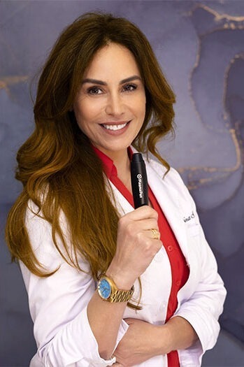 Elmira-white-coat-plasma-pen - Elmira Studio A woman in a lab coat holding a toothbrush.